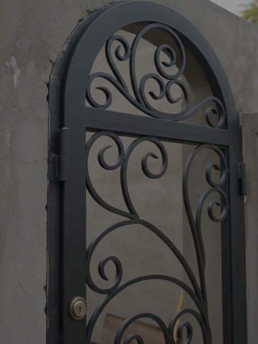 Puerta peatonal de forja artística instalada en el muro de una residencia