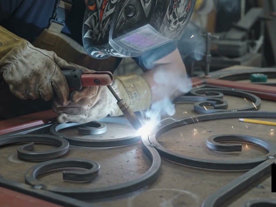 Soldadura de las volutas al bastidor de una puerta de forja en el taller